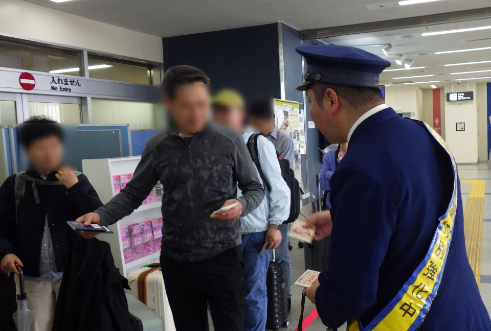 広報用テッシュを配布する家畜防疫官とテッシュを受け取る旅客