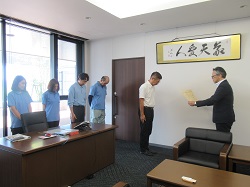 藤尾社長(中央)に大臣感謝状を贈呈する 藤岡地方参事官(右)