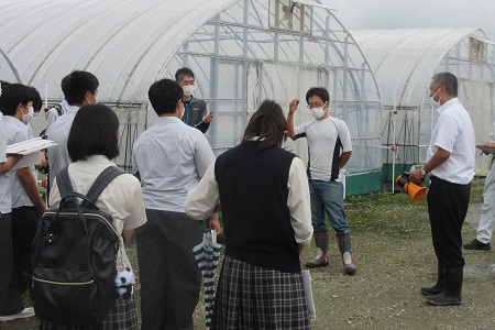 就農啓発交流会で高校生に説明する各川さんの写真