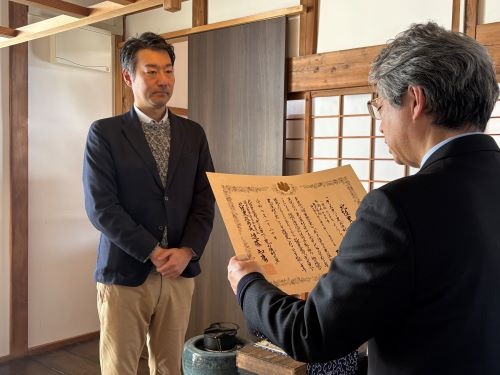 農泊施設にて授与の様子（写真左：（株）HOME HOME NIIGATA 井比代表）