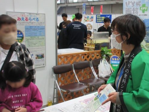 来場者に見えるらべるの説明をする様子