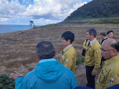 白米（しろよね）千枚田にて営農状況等の説明を受ける鈴木農林水産大臣（中央）