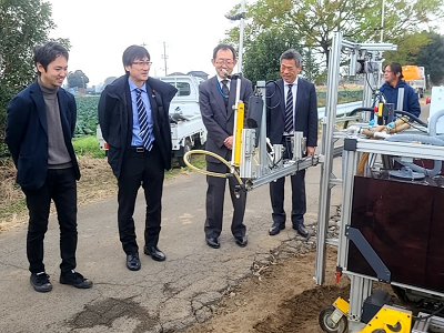 ほ場で農薬散布ロボットの実演を視察する舞立農林水産大臣政務官（左から2人目）