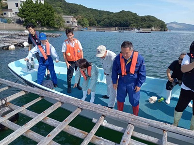 船上でカキ養殖いかだの被災状況の説明を受ける山本農林水産大臣政務官（中央）