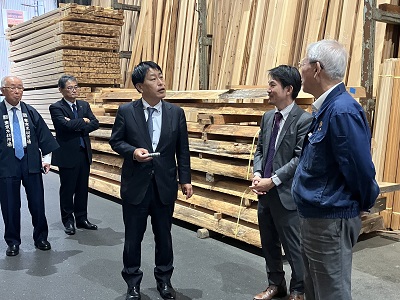 市場で取り扱う木材製品や販売方法（競り売り）の説明を受ける武村農林水産副大臣