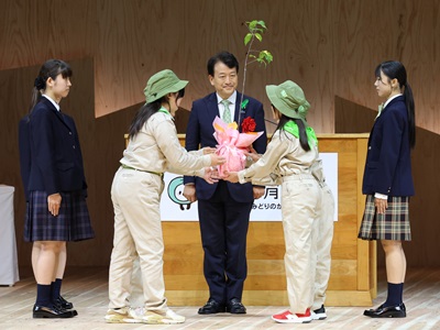 緑の少年団による苗木の受け渡しを見守る笹川農林水産副大臣（中央）