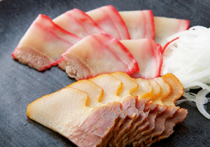 舌の上でとろけるような鯨ベーコン。手前は添加物を一切使用せず、国産のクルミとスコットランドのビート(泥炭)で自家スモークした「ひみつくじら」の特製。