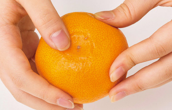 皮が少し浮いたみかんは、外皮と袋をはがすように、指で何回か揉んでいく。