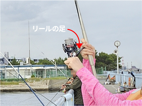 釣りざおは、リールの足が中指と薬指の間にくるようにして握る。初心者は釣りざおの端を持ちがちだが、それは間違い。