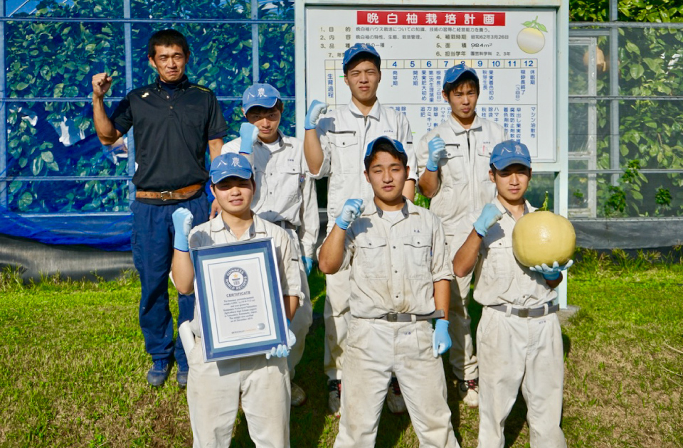 県立八代農業高校園芸科学科果実コース3年の生徒たちと平田先生。手にしているのは、2012年に八代市の農家で収穫された晩白柚のレプリカ。