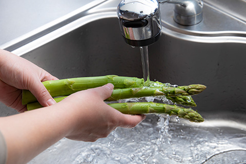 写真：アスパラガスを水で洗う