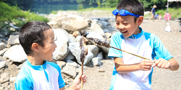 写真:魚の塩焼きを持つ子供たち
