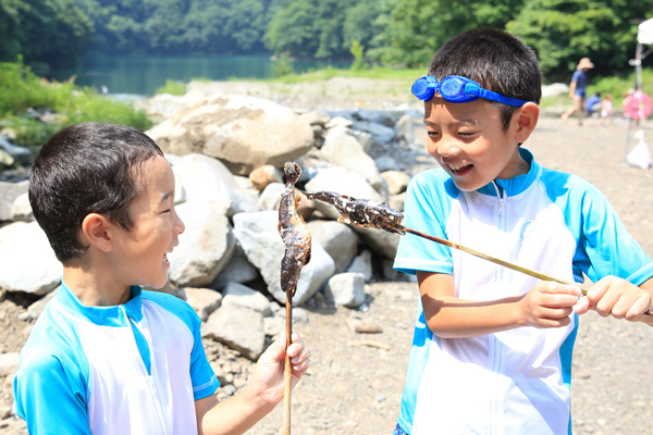 画像：魚の塩焼きを持つ子供たち