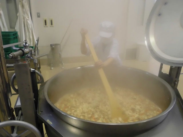 写真：給食用の大釜で煮込む