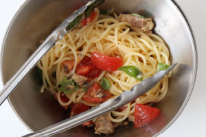 写真：スパゲッティをボウルに入れ具材を混ぜる
