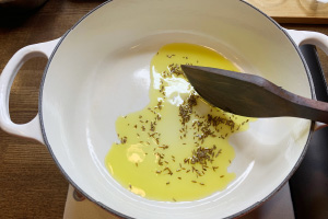 写真:鍋にクミンシードとなたね油を入れて弱火で加熱する