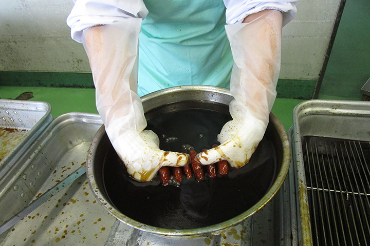 写真:ゼリーフライをソースに浸ける様子