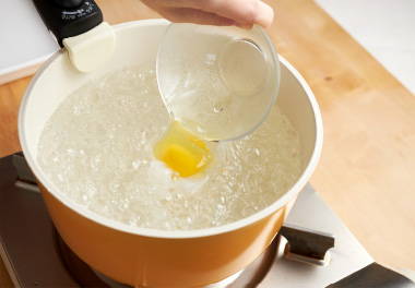 写真：沸騰したお湯を菜箸などでかき混ぜて渦をつくり、渦の中央に卵を入れる
