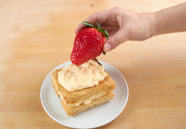 写真：パイとパイの間にクリームを挟み、1粒のいちごを載せて、粉砂糖をかけて出来上がり