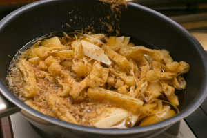 写真:たけのこを入れた鍋に油揚げを入れ、その上に鰹節を振りかけ火をつける