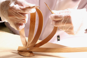 写真:竹片を1枚ずつねじりながら、もう片方の穴にビス止め