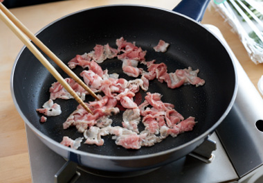 写真：豚肉を炒め、塩、こしょうを振る