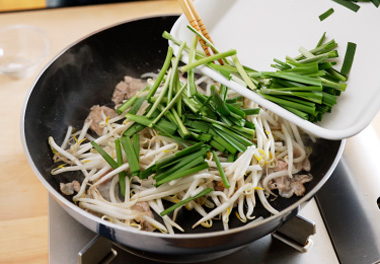 写真：もやし、にらの根元部分を加えて炒め合わせる