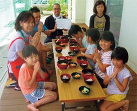 地域住民からいただいた野菜を使い、みんなで作った料理をみんなで食べる風景。