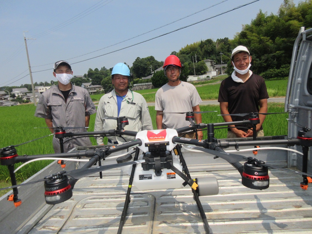 ドローンを前に並ぶ4人の男性