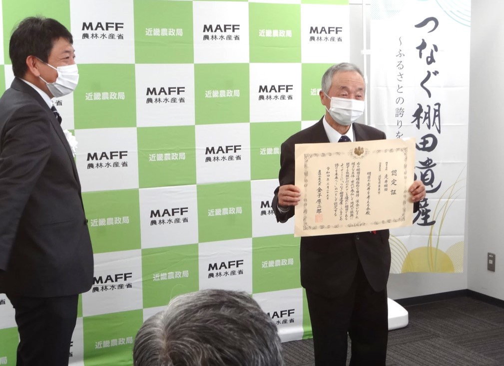 授与された認定証を披露する認定団体の代表者