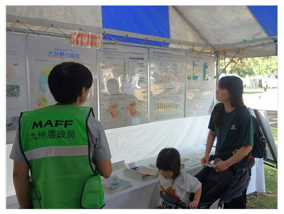 ブース内でパネルを見る親子と説明している職員